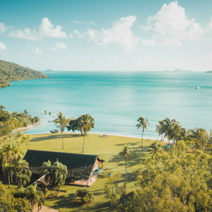 Aerial view of Villa Paradise Cove in Airlie Beach, Whitsundays — a 4,000-acre private coastal wedding estate with beachfront lawns, palm trees, and turquoise Coral Sea waters.